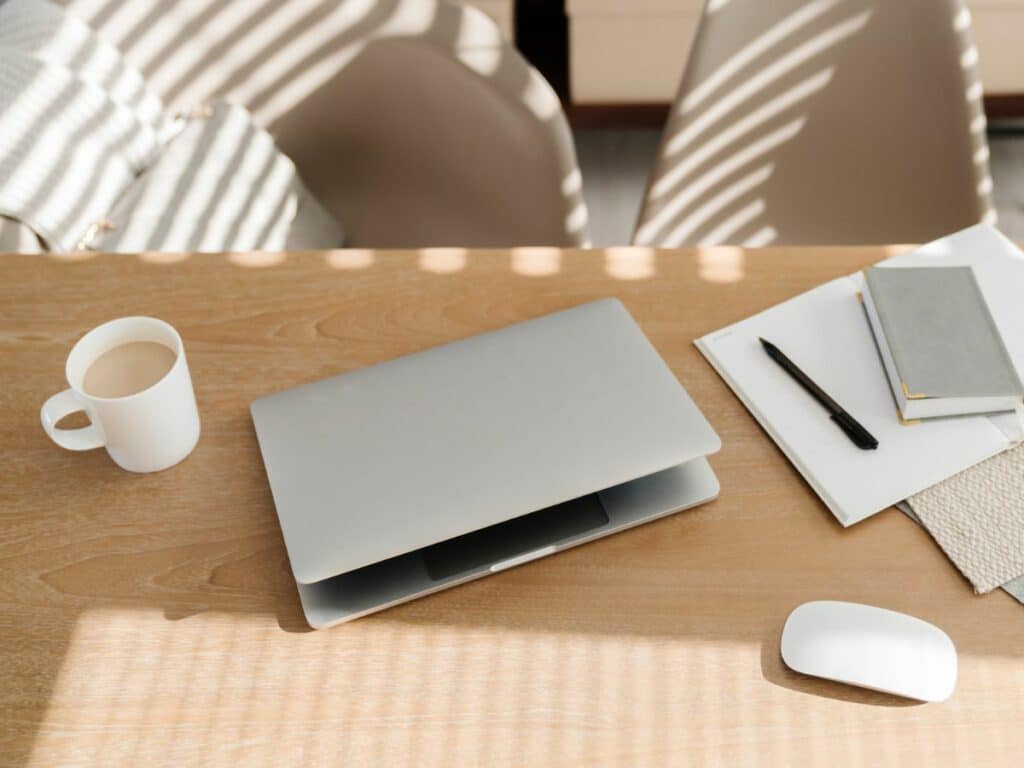 Schreibtisch mit Laptop, Kaffeetasse, Notizblock, Maus