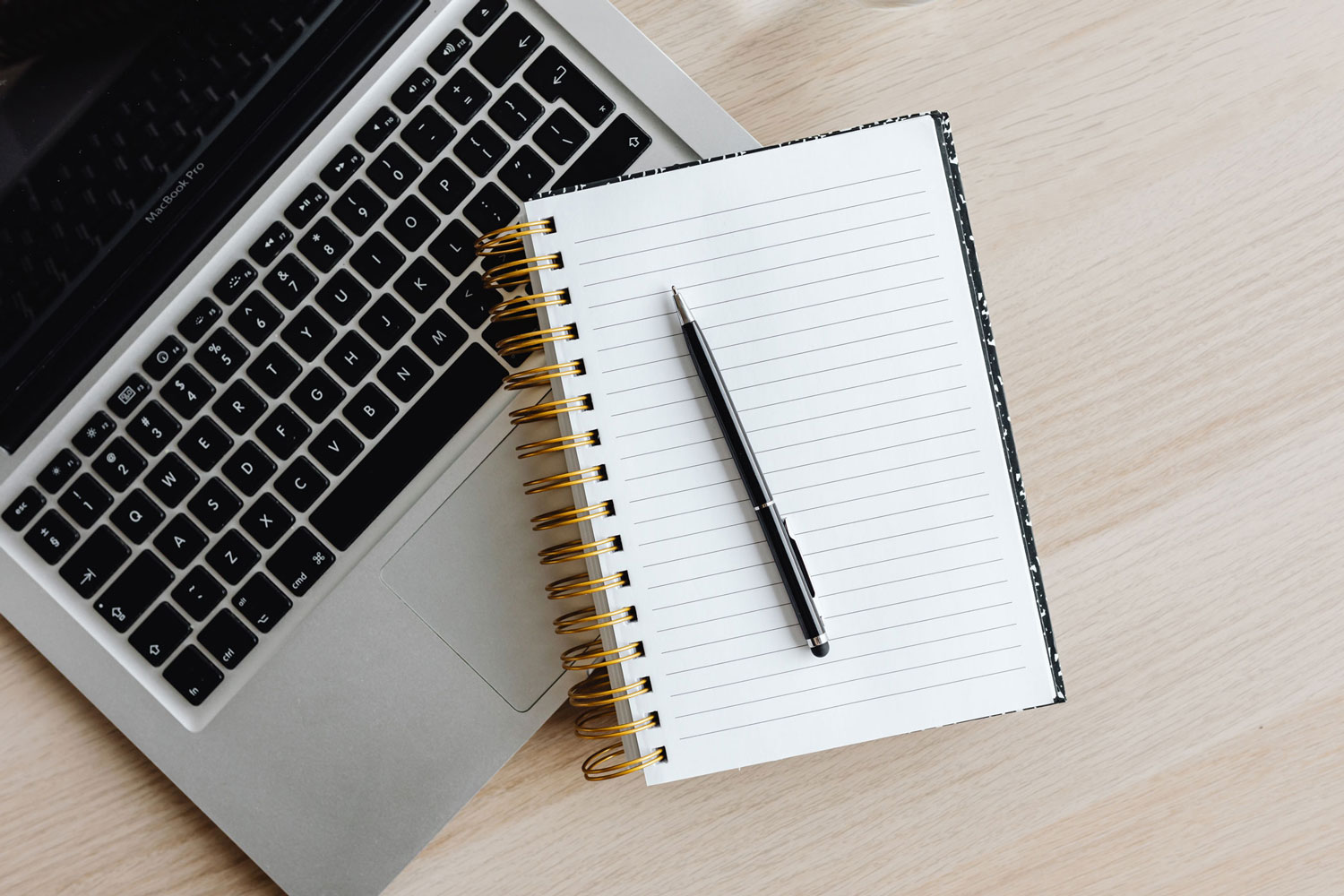 Laptop mit Notizblock und Stift daneben